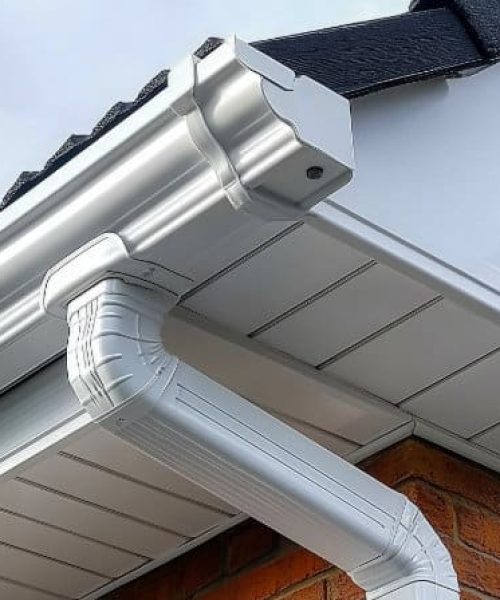 The white aluminum guttering is beautifully installed alongside Closeup view of old white gutter system with soffit vent, window with white frame, gutter guard, downspout, decorative trim molding, on corner of brick luxury house --chaos 45 --ar 16:9 --stylize 750 --v 6.1 Job ID: b47b6ee0-33e2-48cf-b0db-442c00769eca